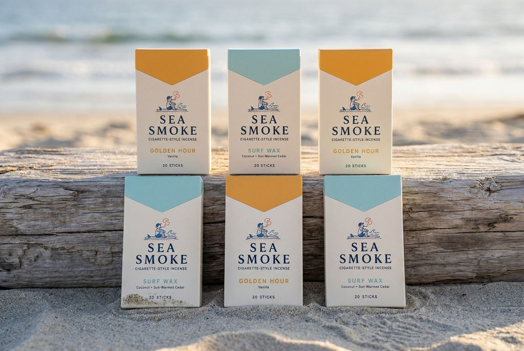 Six Sea Smoke packs in two rows on a driftwood log, three Golden Hour and three Surf Wax